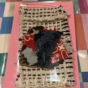 Beige decorative patch.  The patch has a pin has a pin as closure.